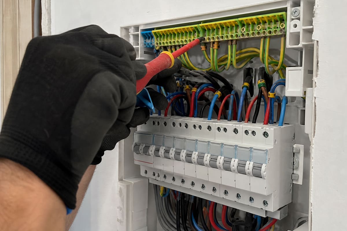 mains contrôlant un tableau électrique ouvert