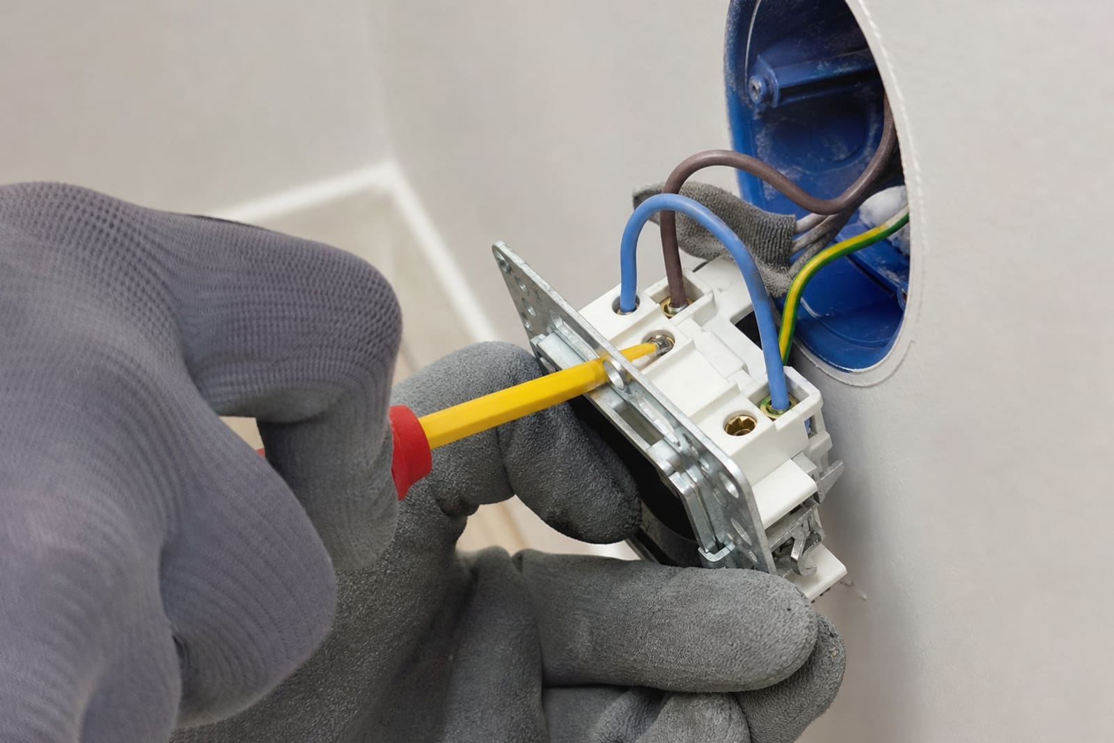mains raccordant une prise murale électrique
